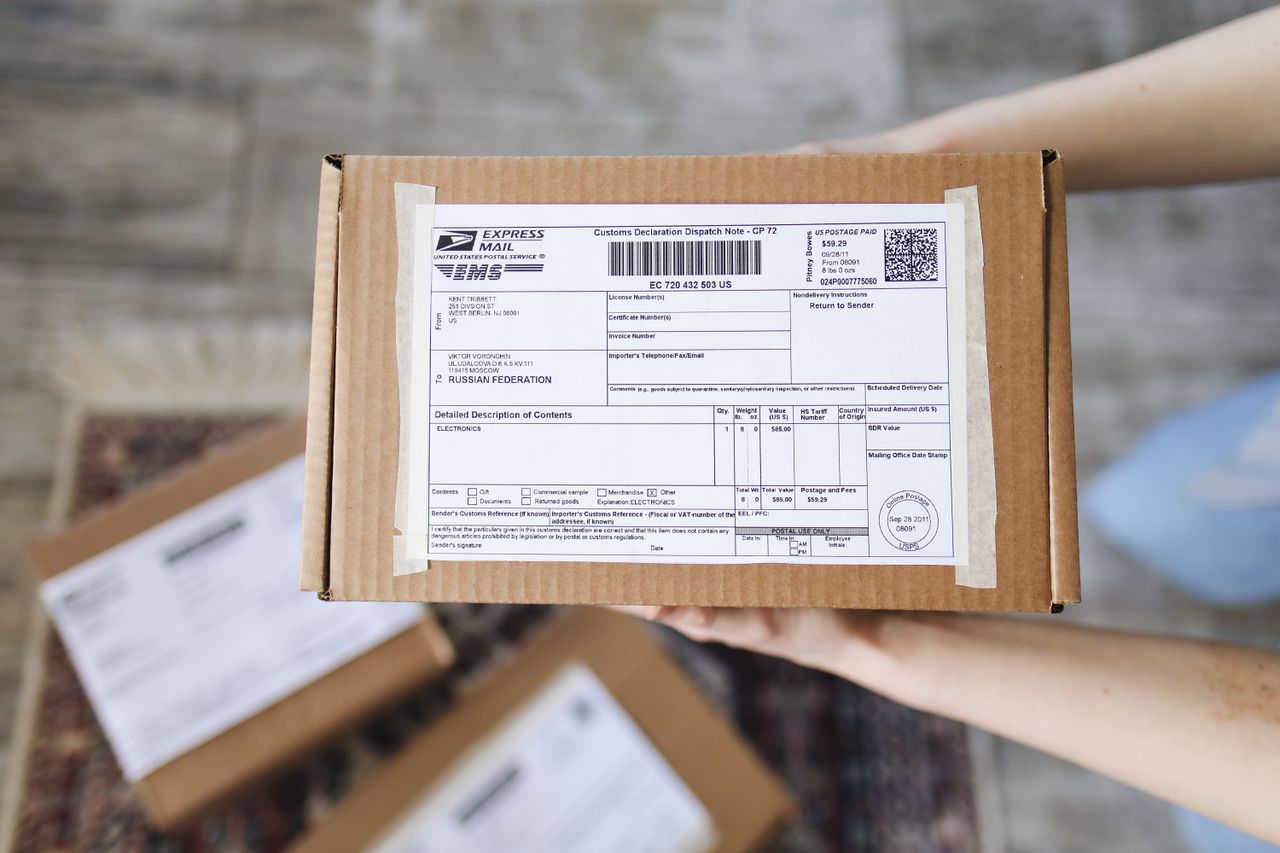 Top view of hands holding an express mail parcel with a customs declaration.
