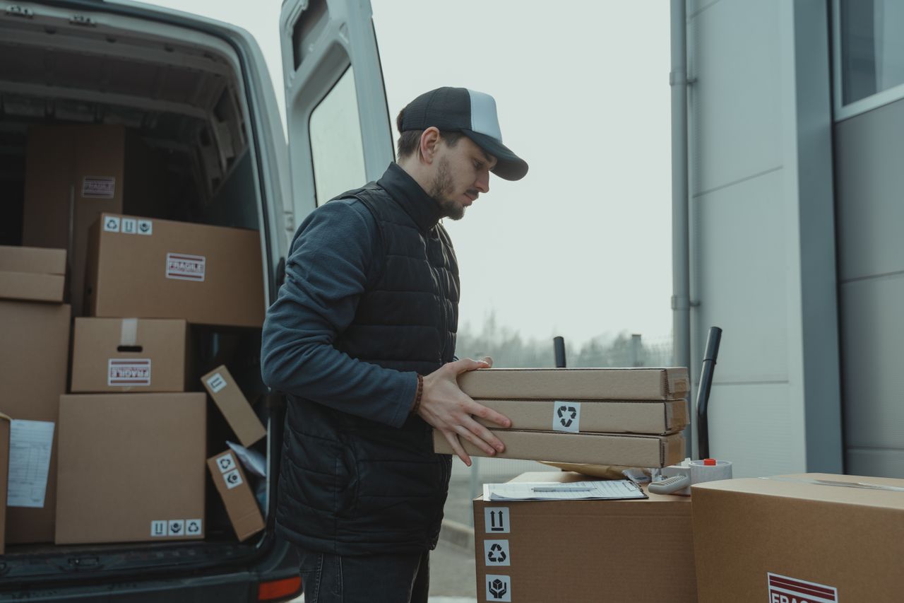 why-choose-us Delivery driver handling cardboard boxes during shipping at a commercial building.