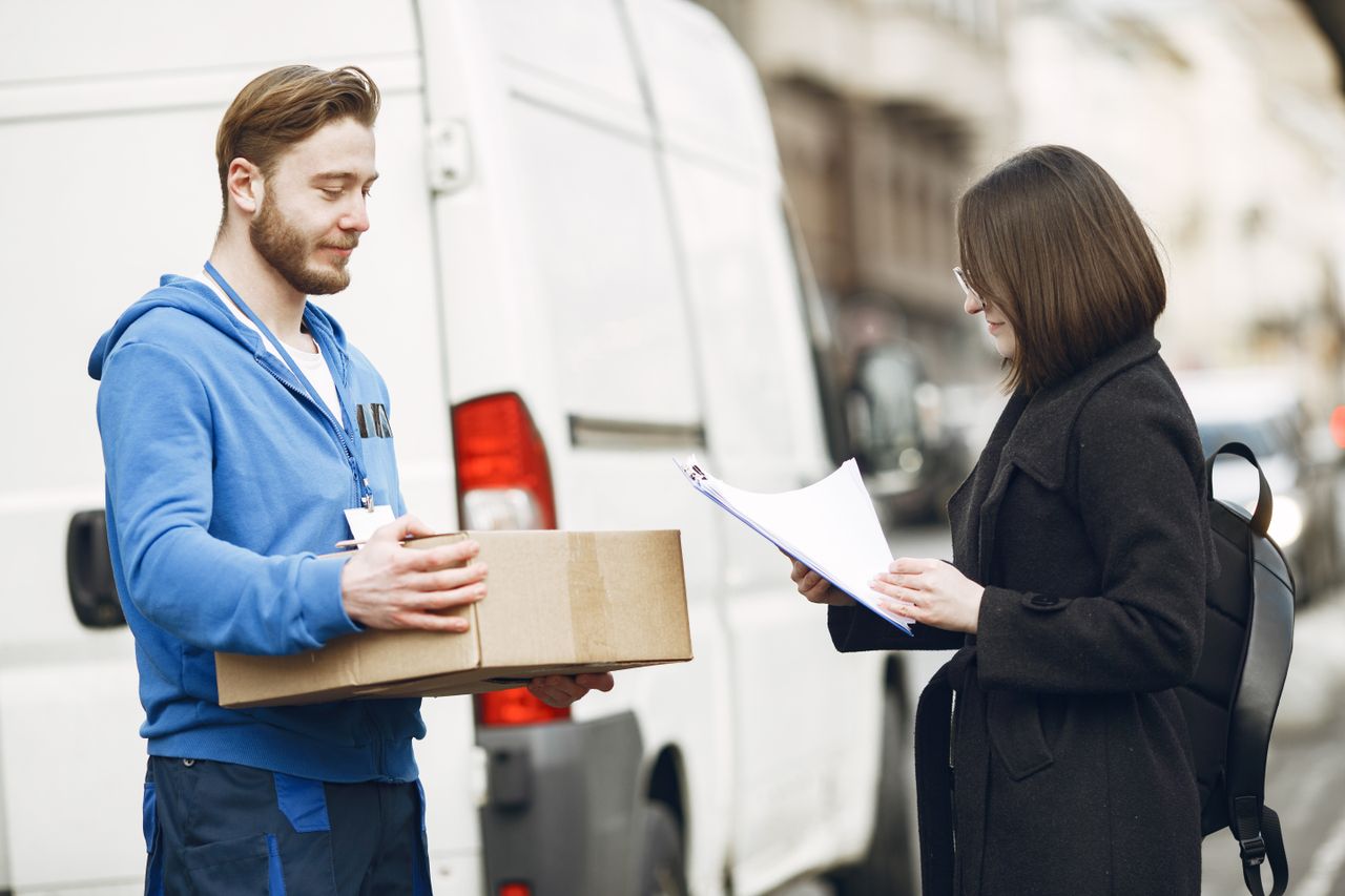 services-03 A courier hands over a package to a woman client on a city street, facilitating delivery service.