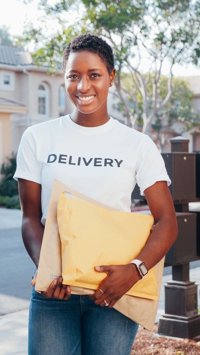 Confident delivery woman in uniform holding parcels, showcasing professional courier service.